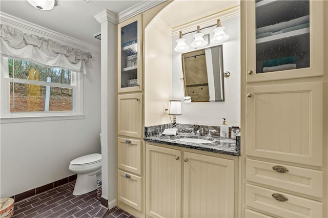 bathroom with baseboards, toilet, vanity, and crown molding