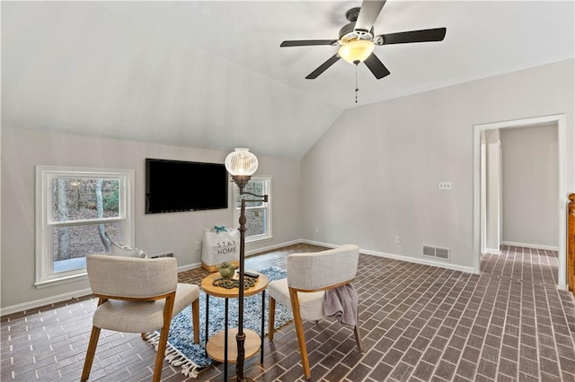 living area with brick floor, visible vents, baseboards, and vaulted ceiling