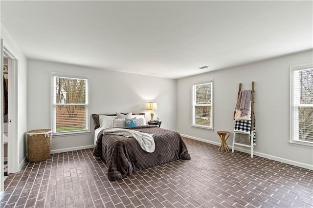 bedroom with brick floor, visible vents, and baseboards