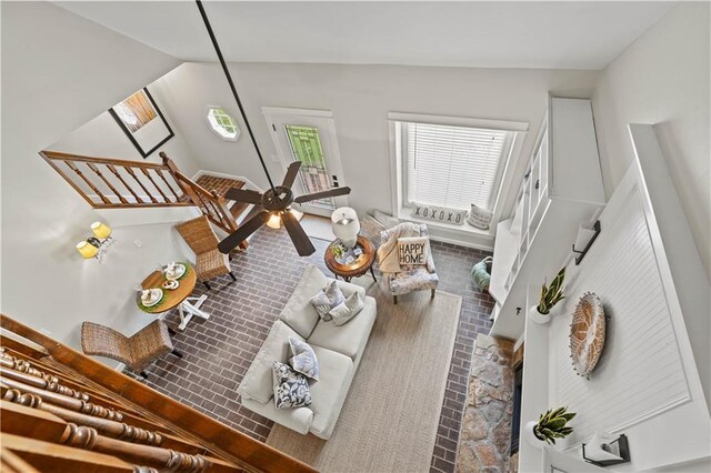 living area featuring a warm lit fireplace, brick floor, lofted ceiling, and baseboards