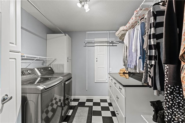 laundry area with dark floors, cabinet space, washer and clothes dryer, and a textured ceiling