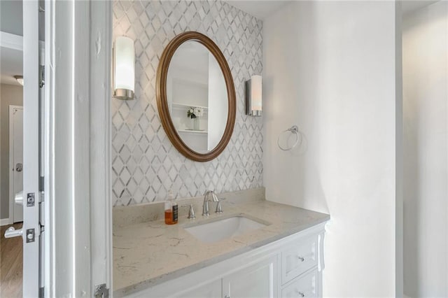 bathroom with wallpapered walls and vanity