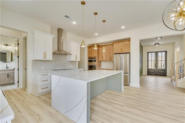 4265 Haynes Cir, Snellville, GA 30039 - kitchen featuring hanging light fixtures, stainless steel appliances, light stone countertops, white cabinets, and wall chimney exhaust hood