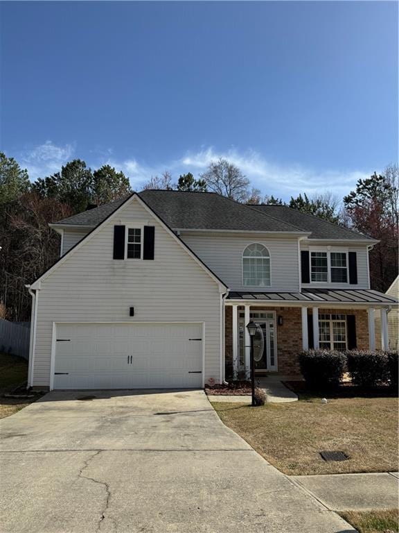 traditional-style house with a standing seam roof, concrete driveway, an attached garage, and metal roof