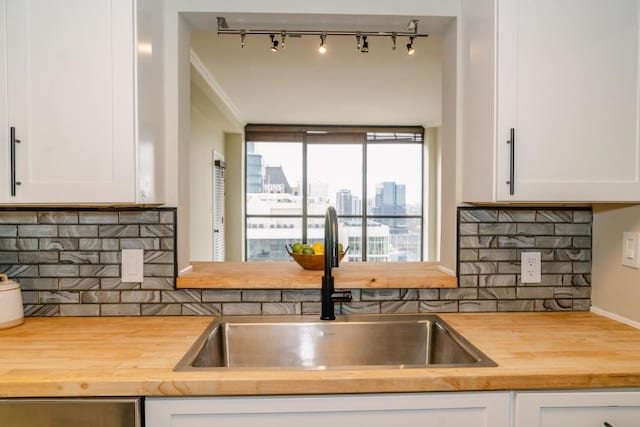 kitchen featuring a view of city, backsplash, white cabinets, a sink, and wood counters