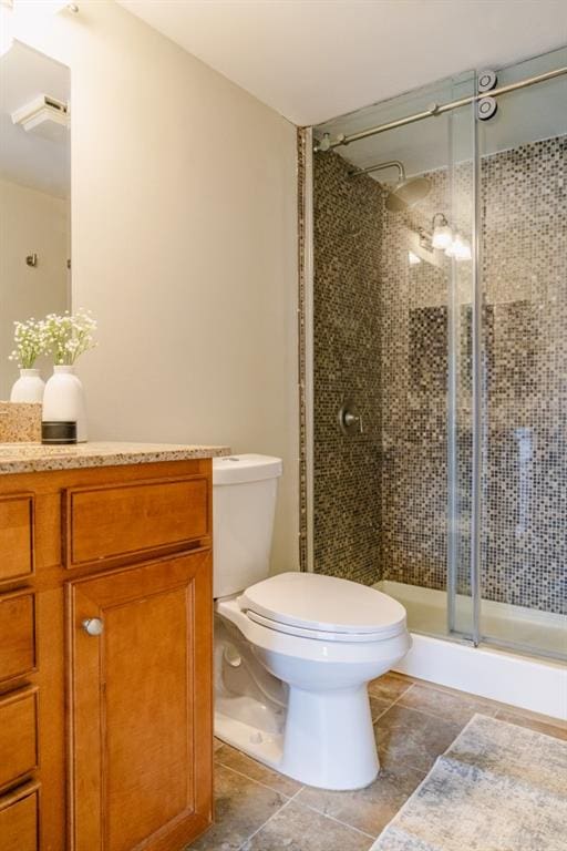 bathroom featuring vanity, a shower stall, toilet, and tile patterned floors