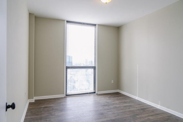 empty room with a wall of windows, baseboards, and wood finished floors