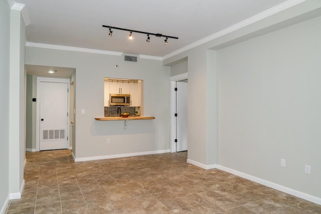 unfurnished room with baseboards, visible vents, and crown molding