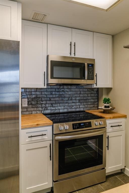 kitchen featuring appliances with stainless steel finishes, white cabinets, and wood counters