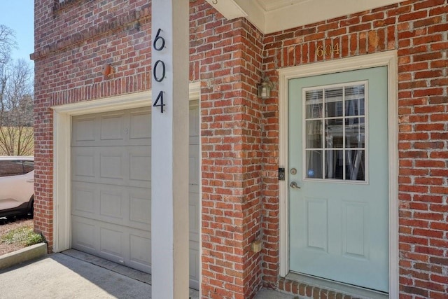 view of exterior entry featuring brick siding and an attached garage