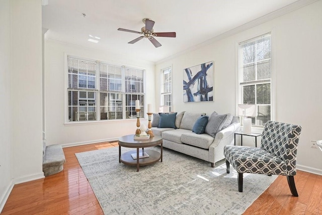 living area featuring ceiling fan, baseboards, crown molding, and wood finished floors