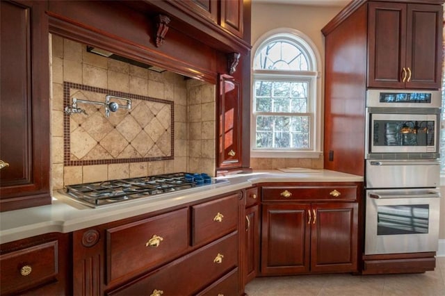 kitchen with light tile patterned floors, backsplash, and stainless steel appliances