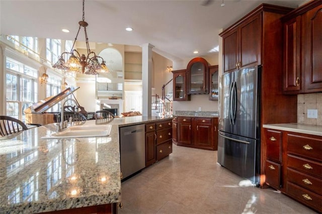 kitchen featuring sink, stainless steel appliances, backsplash, a chandelier, and decorative light fixtures