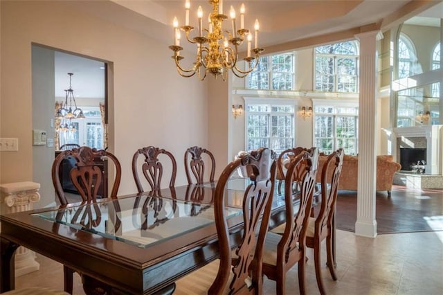 dining room featuring ornate columns, a wealth of natural light, and a chandelier