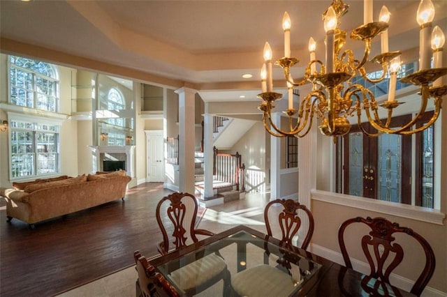 dining room featuring hardwood / wood-style flooring, ornate columns, french doors, and an inviting chandelier