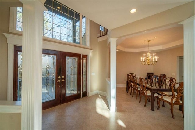 foyer entrance featuring a chandelier, french doors, a towering ceiling, and a raised ceiling