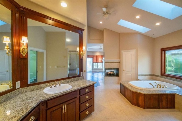 bathroom with a skylight, vanity, ceiling fan, independent shower and bath, and tile patterned flooring