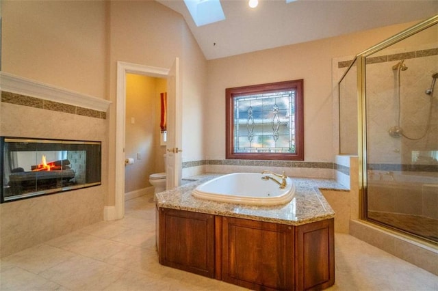 bathroom with tile patterned floors, a multi sided fireplace, vaulted ceiling with skylight, toilet, and shower with separate bathtub