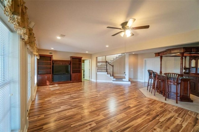 living room featuring light wood-type flooring, ceiling fan, and a healthy amount of sunlight