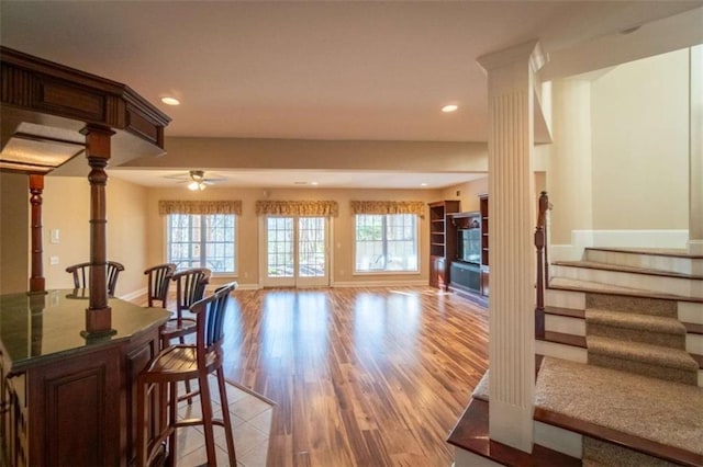 interior space featuring light wood-type flooring, decorative columns, and ceiling fan