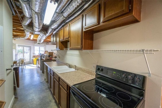 kitchen featuring concrete flooring, black range with electric stovetop, and sink