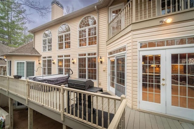 wooden terrace with area for grilling, french doors, and a hot tub