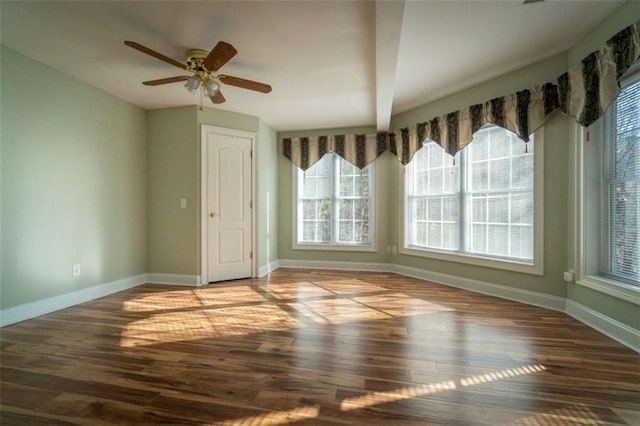 empty room with a wealth of natural light, hardwood / wood-style floors, and ceiling fan