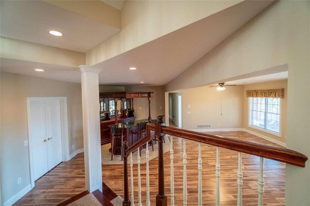 hall with vaulted ceiling, wood-type flooring, and decorative columns