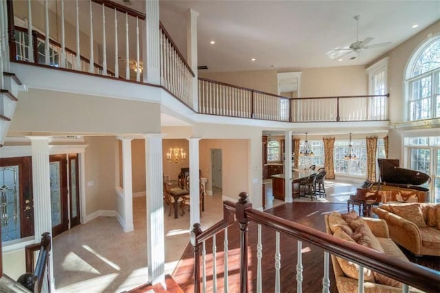 interior space with decorative columns, plenty of natural light, ceiling fan with notable chandelier, and a high ceiling