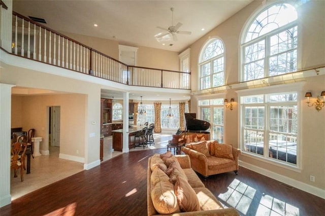 living room with hardwood / wood-style floors, ceiling fan, and a high ceiling