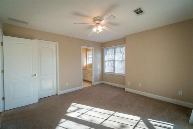 unfurnished bedroom featuring ceiling fan, light carpet, and ensuite bath