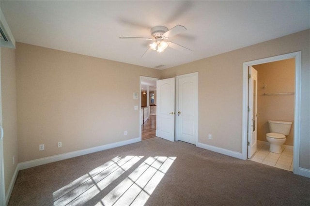 unfurnished bedroom featuring ceiling fan, light colored carpet, ensuite bathroom, and a closet