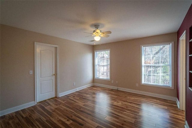 spare room with dark hardwood / wood-style floors, ceiling fan, and a healthy amount of sunlight