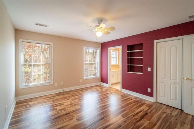 unfurnished bedroom with ceiling fan, wood-type flooring, and ensuite bath