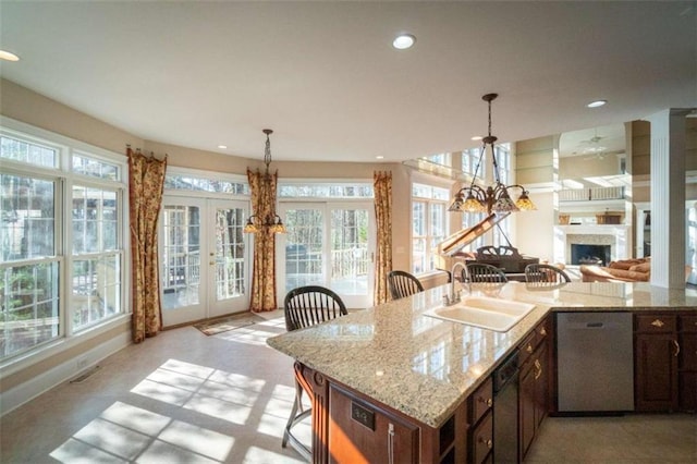 kitchen featuring stainless steel dishwasher, light stone countertops, sink, and french doors