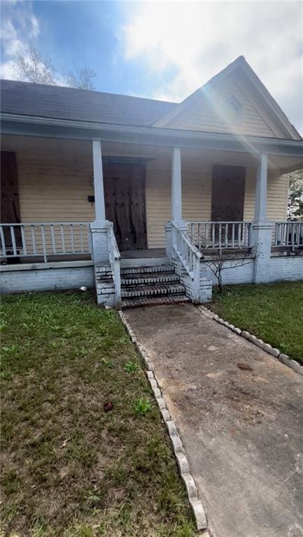 entrance to property with a porch and a lawn