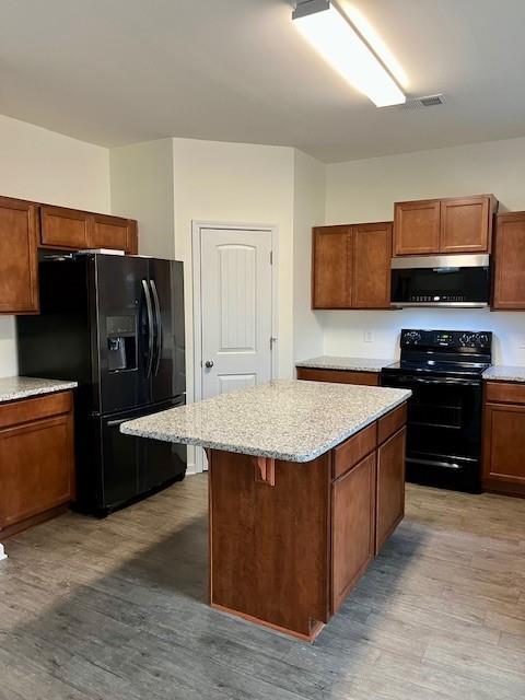 kitchen with black appliances, a breakfast bar, a center island, and light hardwood / wood-style flooring