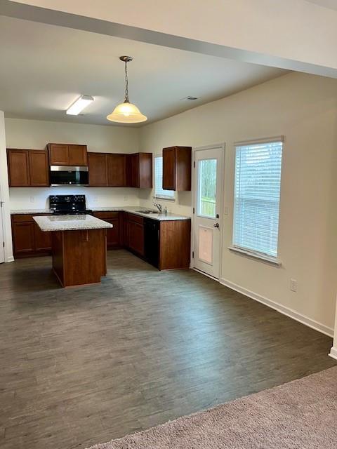 kitchen featuring sink, a kitchen island, dark hardwood / wood-style floors, decorative light fixtures, and black range