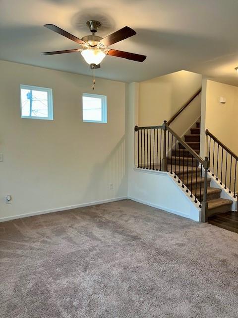 interior space with ceiling fan and dark carpet