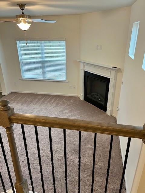 unfurnished living room featuring ceiling fan and carpet floors