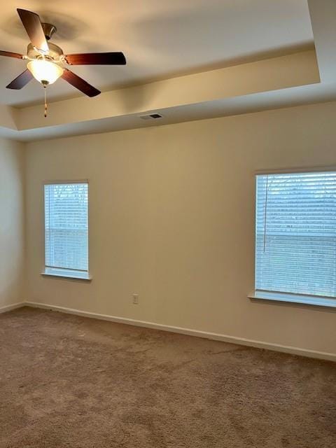 unfurnished room featuring a tray ceiling, ceiling fan, and carpet flooring