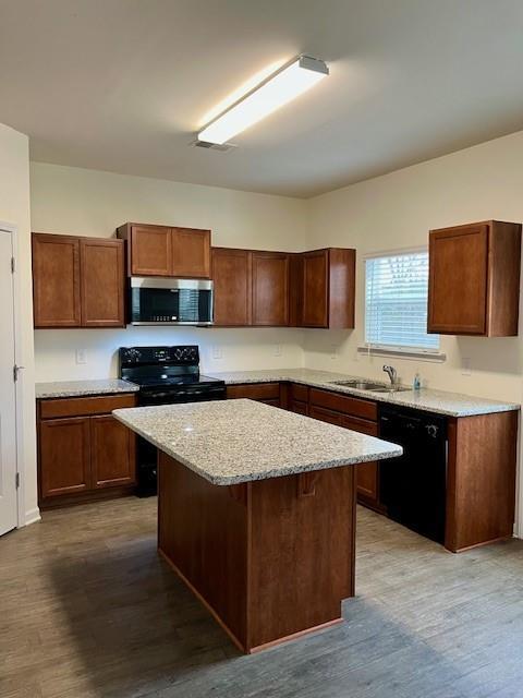 kitchen with a breakfast bar, dark wood-type flooring, sink, black appliances, and a center island