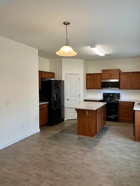 kitchen with dark hardwood / wood-style flooring, a center island, hanging light fixtures, and black appliances