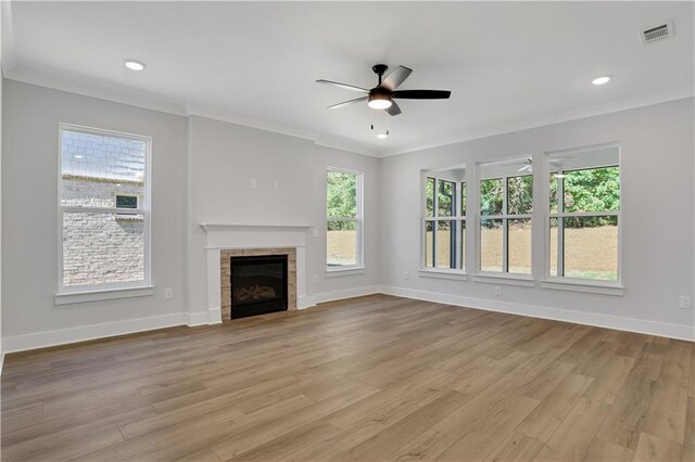 unfurnished living room with ornamental molding, light hardwood / wood-style floors, ceiling fan, and a fireplace