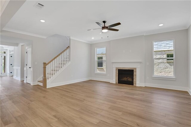 unfurnished living room featuring a healthy amount of sunlight, light hardwood / wood-style floors, a tiled fireplace, and ceiling fan