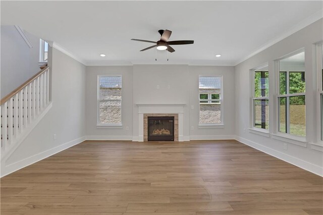 unfurnished living room featuring ceiling fan, ornamental molding, a fireplace, and light hardwood / wood-style floors