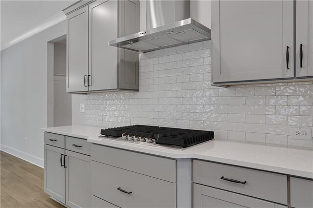 kitchen featuring wall chimney exhaust hood, decorative backsplash, gas stovetop, and light wood-type flooring