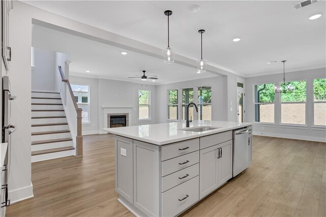 kitchen with hanging light fixtures, light hardwood / wood-style floors, dishwasher, a center island with sink, and sink