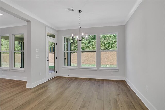 unfurnished dining area featuring ornamental molding, light wood-type flooring, and a chandelier