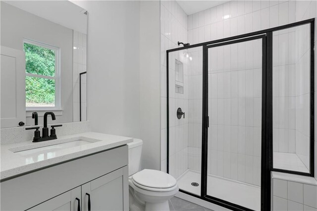 bathroom featuring tile patterned flooring, vanity, toilet, and an enclosed shower